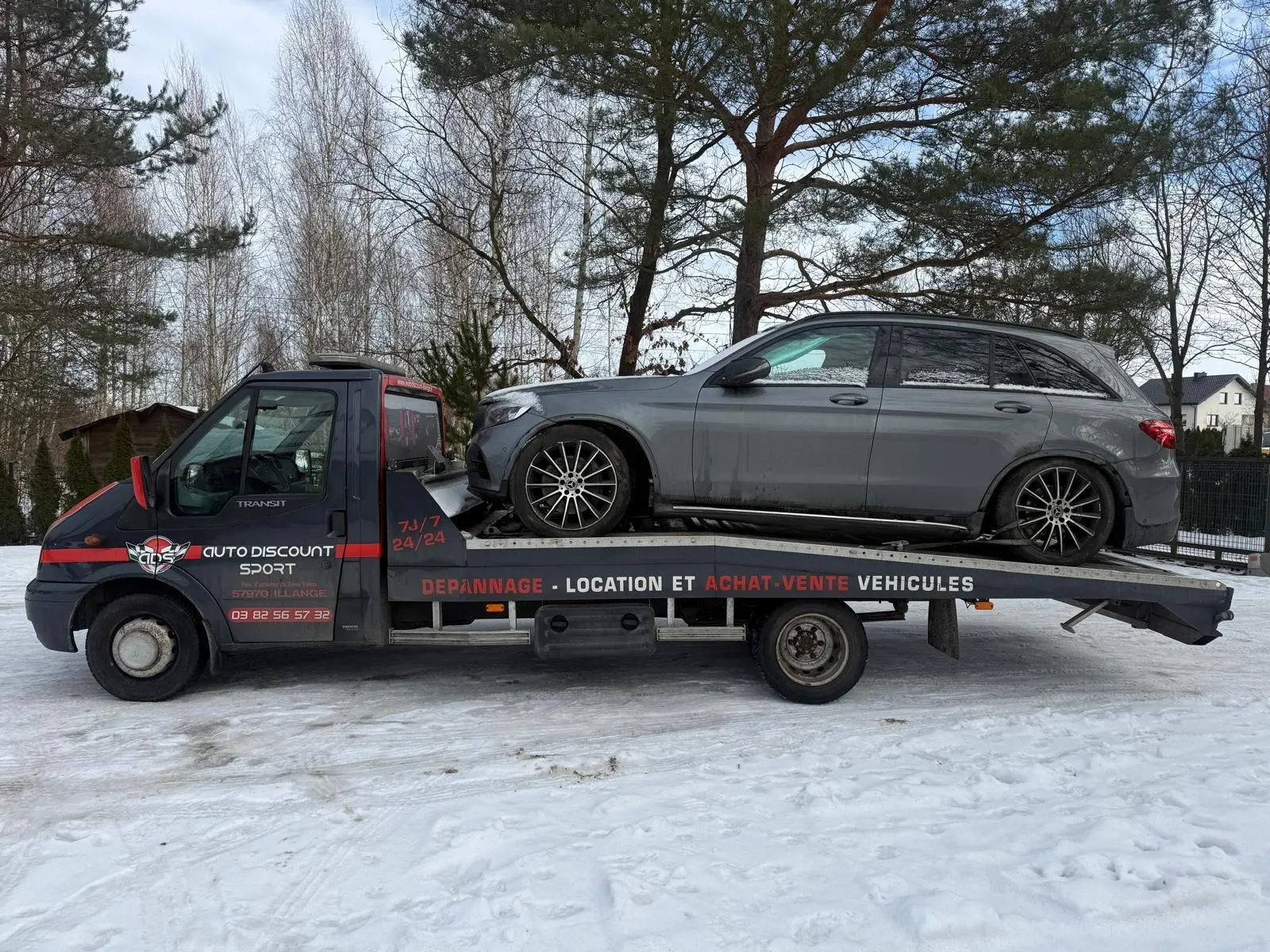 SUV załadowany na lawetę podczas zimowego transportu