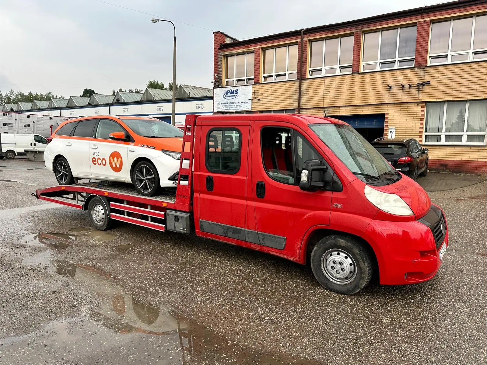 Sprawny samochód osobowy kombi przewożony na platformie czerwonej lawety